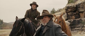 Movie still from “True Grit” (2010), directed by Ethan Coen – A man and a woman on horses in a field; Medium shot, Low angle