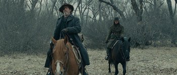 Movie still from “True Grit” (2010), directed by Ethan Coen – A man and a woman on horses in a wooded area; Medium shot, Low angle