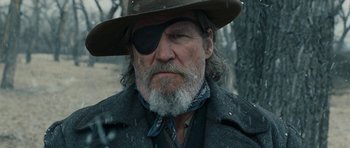 Movie still from “True Grit” (2010), directed by Ethan Coen – An old man with a beard wearing a hat and eye patch; Close Up shot, Low angle