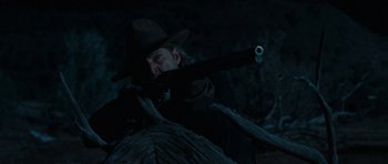 Movie still from “True Grit” (2010), directed by Ethan Coen – A man in a hat is holding a gun; Medium shot, Over the shoulder angle