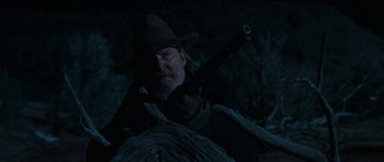 Movie still from “True Grit” (2010), directed by Ethan Coen – A man with a gun in his hand and a hat on; Medium shot, Low angle