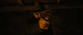 Movie still from “True Grit” (2010), directed by Ethan Coen – A man wearing a hat and holding a gun in his hand; Close Up shot, Over the shoulder angle