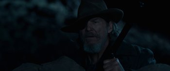 Movie still from “True Grit” (2010), directed by Ethan Coen – A person wearing a hat and holding a gun; Close Up shot, Over the shoulder angle