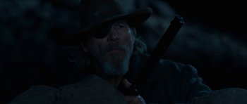 Movie still from “True Grit” (2010), directed by Ethan Coen – A person wearing a hat and holding a gun; Close Up shot, Over the shoulder angle