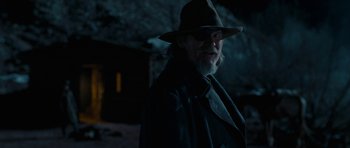 Movie still from “True Grit” (2010), directed by Ethan Coen – An older man wearing a hat and a leather jacket; Close Up shot, Over the shoulder angle