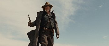 Movie still from “True Grit” (2010), directed by Ethan Coen – An older man in a hat and a long coat; Medium shot, Low angle