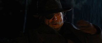 Movie still from “True Grit” (2010), directed by Ethan Coen – An older man wearing a hat and a black coat; Close Up shot, Over the shoulder angle