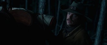 Movie still from “True Grit” (2010), directed by Ethan Coen – A man in a cowboy hat holding on to a horse; Close Up shot, Over the shoulder angle