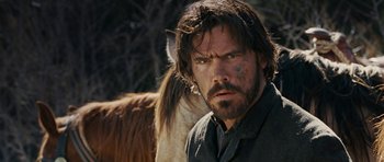 Movie still from “True Grit” (2010), directed by Ethan Coen – A person with a horse in the background; Close Up shot, Over the shoulder angle