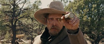 Movie still from “True Grit” (2010), directed by Ethan Coen – A man in a hat holding a telescope; Close Up shot, Over the shoulder angle