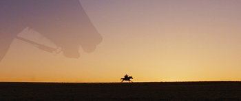 Movie still from “True Grit” (2010), directed by Ethan Coen – A person riding a horse in a field at sunset; Extreme Wide shot, Low angle