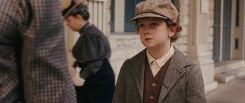 Movie still from “True Grit” (2010), directed by Ethan Coen – A young boy wearing a suit and a hat; Close Up shot, Over the shoulder angle