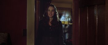 Movie still from “Trust” (2010), directed by David Schwimmer – A young woman standing in a doorway with a smile on her face; Medium shot, Over the shoulder angle