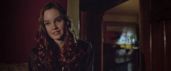 Movie still from “Trust” (2010), directed by David Schwimmer – A woman with long red curly hair smiling for the camera; Close Up shot, Over the shoulder angle