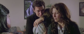 Movie still from “Trust” (2010), directed by David Schwimmer – A man and a woman hug while a woman looks on; Medium shot, Over the shoulder angle