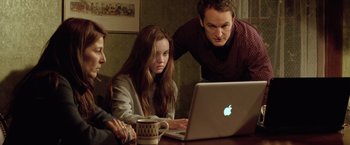 Movie still from “Trust” (2010), directed by David Schwimmer – A group of people sitting at a table looking at a laptop; Medium shot, Over the shoulder angle