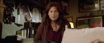 Movie still from “Trust” (2010), directed by David Schwimmer – A woman sitting at a table looking down at a piece of paper; Medium shot, Over the shoulder angle