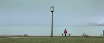 Movie still from “Trust” (2010), directed by David Schwimmer – A woman sitting on a bench near a lamp post; Extreme Wide shot, High angle