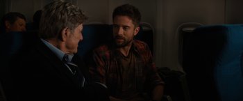 Movie still from “Truth” (2015), directed by James Vanderbilt – Two men are sitting on a plane and talking to each other; Medium shot, Over the shoulder angle