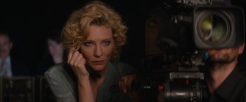 Movie still from “Truth” (2015), directed by James Vanderbilt – A woman with curly blonde hair is holding a camera; Close Up shot, Over the shoulder angle