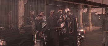 Movie still from “Tsotsi” (2005), directed by Gavin Hood – A group of men standing next to each other in front of a building; Medium shot, Low angle