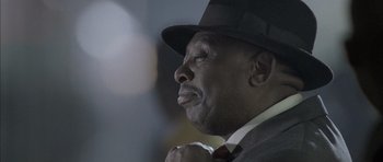 Movie still from “Tsotsi” (2005), directed by Gavin Hood – A man in a suit and a top hat; Close Up shot, Low angle