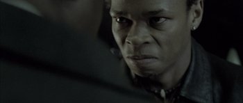 Movie still from “Tsotsi” (2005), directed by Gavin Hood – A person's face in a dark room; Extreme Close Up shot, Low angle