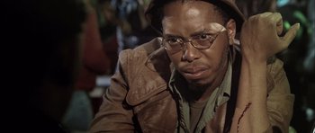 Movie still from “Tsotsi” (2005), directed by Gavin Hood – A person wearing glasses and a leather jacket; Close Up shot, Low angle