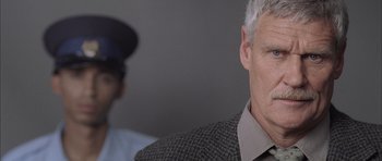 Movie still from “Tsotsi” (2005), directed by Gavin Hood – An older man wearing a jacket and a hat; Close Up shot, Over the shoulder angle