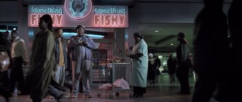 Movie still from “Tsotsi” (2005), directed by Gavin Hood – A man and a woman standing in front of something fishy sign; Wide shot, Low angle