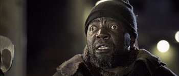 Movie still from “Tsotsi” (2005), directed by Gavin Hood – A person wearing a hat and a coat; Close Up shot, Low angle