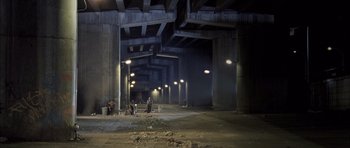 Movie still from “Tsotsi” (2005), directed by Gavin Hood – A couple of people standing under a bridge at night; Extreme Wide shot, High angle