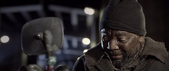 Movie still from “Tsotsi” (2005), directed by Gavin Hood – A man in a black coat and a black hat; Extreme Close Up shot, Low angle