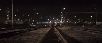 Movie still from “Tsotsi” (2005), directed by Gavin Hood – A man standing on a train track at night time; Extreme Wide shot, High angle