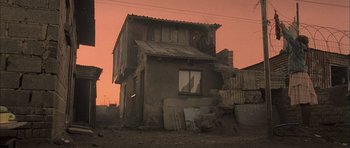 Movie still from “Tsotsi” (2005), directed by Gavin Hood – An old building with a broken window in the middle of the day; Extreme Wide shot, Low angle