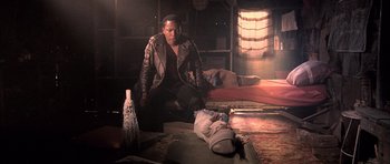 Movie still from “Tsotsi” (2005), directed by Gavin Hood – A man sitting on the floor next to a dead body; Medium shot, Low angle