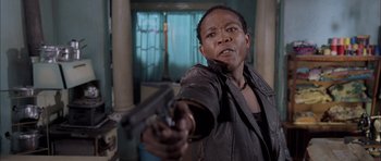 Movie still from “Tsotsi” (2005), directed by Gavin Hood – A man holding a gun in a room; Close Up shot, Low angle