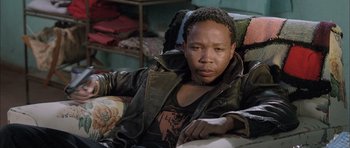 Movie still from “Tsotsi” (2005), directed by Gavin Hood – A person sitting on a couch wearing a leather jacket; Close Up shot, Low angle