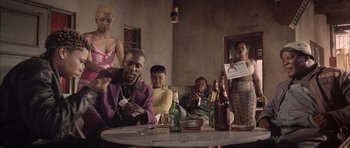 Movie still from “Tsotsi” (2005), directed by Gavin Hood – A group of people sitting at a table with drinks; Medium shot, Low angle
