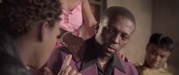 Movie still from “Tsotsi” (2005), directed by Gavin Hood – A man sitting in front of a woman while a woman stands behind him; Close Up shot, Low angle