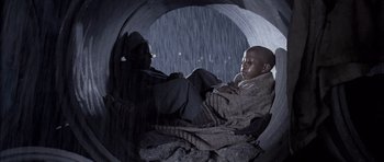 Movie still from “Tsotsi” (2005), directed by Gavin Hood – Two men are sitting in a pipe in the dark; Medium shot, Low angle