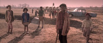 Movie still from “Tsotsi” (2005), directed by Gavin Hood – A group of people standing in a field; Medium shot, High angle