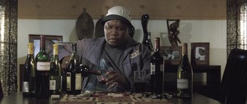 Movie still from “Tsotsi” (2005), directed by Gavin Hood – A man sitting at a table holding a wine glass; Close Up shot, Low angle
