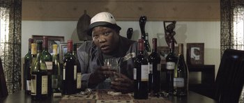 Movie still from “Tsotsi” (2005), directed by Gavin Hood – A man sitting at a table holding a wine glass; Close Up shot, Low angle