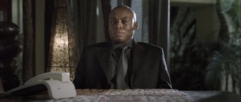 Movie still from “Tsotsi” (2005), directed by Gavin Hood – A man sitting at a table in front of a keyboard; Close Up shot, Low angle