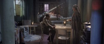 Movie still from “Tsotsi” (2005), directed by Gavin Hood – A man sitting at a table with a woman; Wide shot, High angle