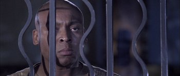Movie still from “Tsotsi” (2005), directed by Gavin Hood – A person behind a metal fence; Close Up shot, Low angle