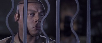 Movie still from “Tsotsi” (2005), directed by Gavin Hood – A person behind a fence; Close Up shot, Low angle