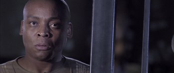 Movie still from “Tsotsi” (2005), directed by Gavin Hood – A person with a sword in a dark room; Close Up shot, Over the shoulder angle