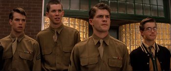 Movie still from “Tucker: The Man and His Dream” (1988), directed by Francis Ford Coppola – Two young men in uniform standing next to each other in front of a building; Medium shot, Low angle